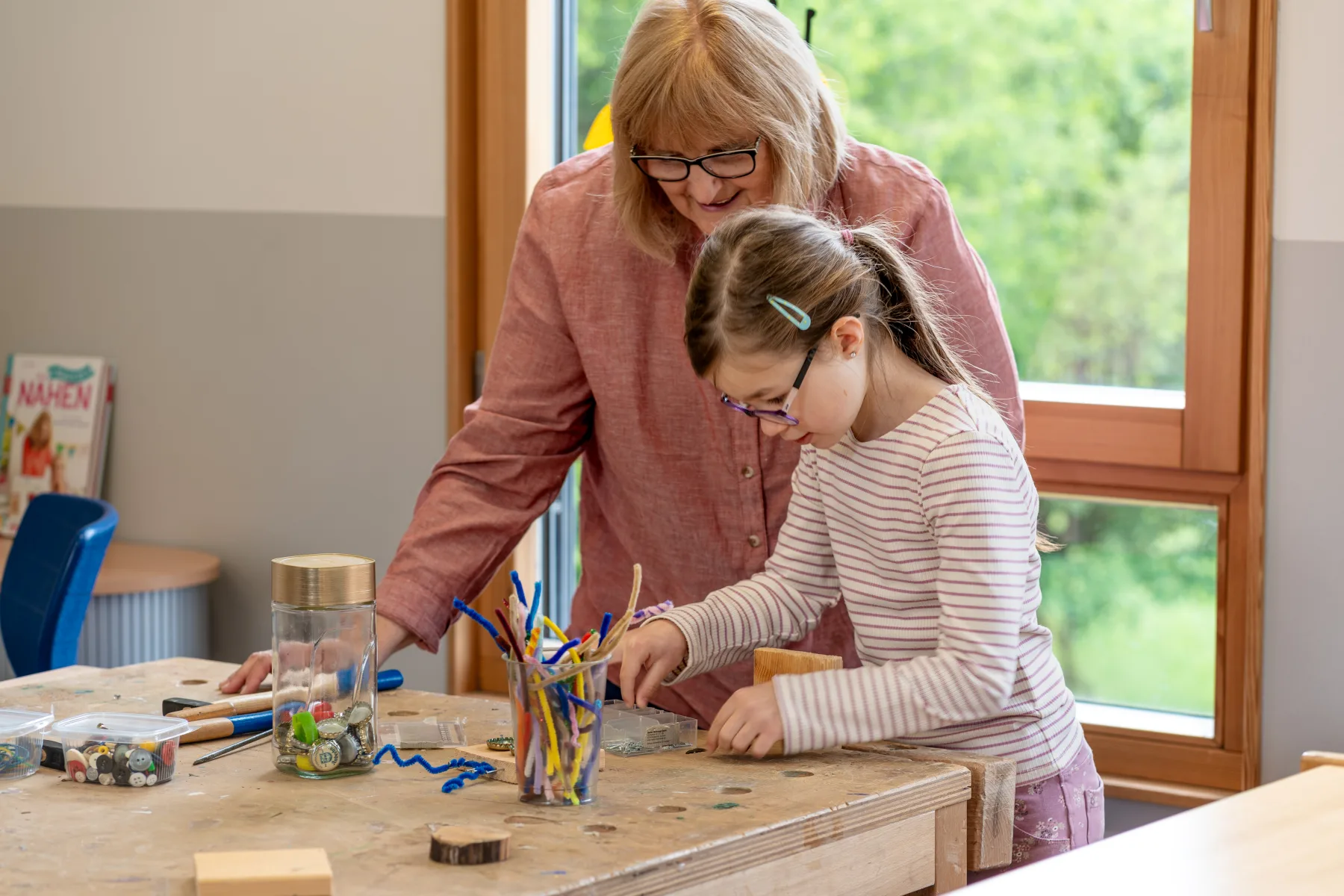 Betreuungskraft begleitet ein Kind beim Werken in der Schulkindbetreuung